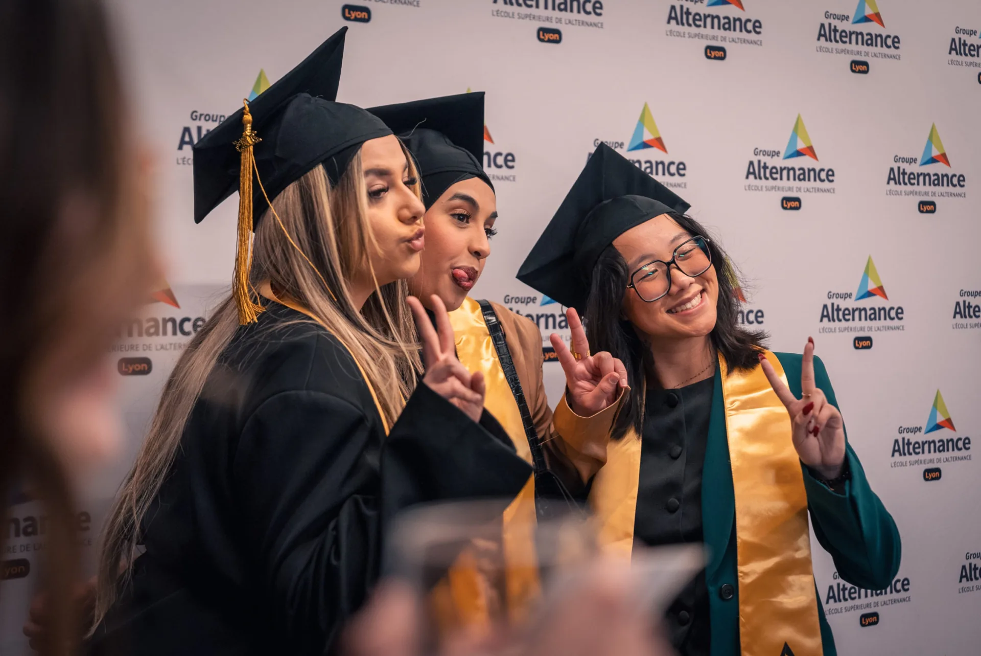 Trois jeunes diplômées avec toque et étole posant lors d'une cérémonie de remise de diplômes